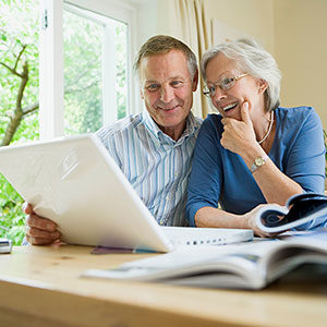 older couple looking at computer and travel guide books