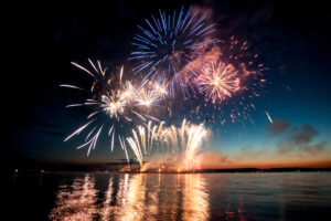 Holiday fireworks above water with reflection on the black sky