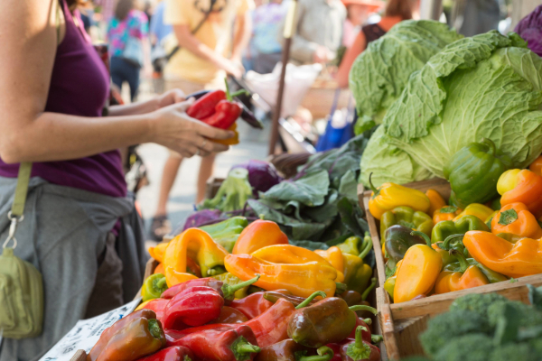 person picking up vegetables at the outdoor market